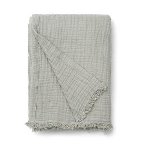 Light gray textured throw blanket folded with a fringed edge